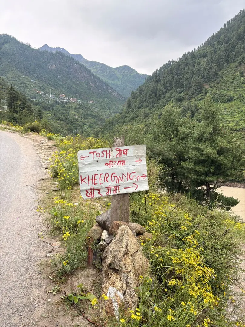 A hand-painted signpost for Tosh and Kheerganga on a mountain road, Parvati Valley. Photograph by Arav Jain.