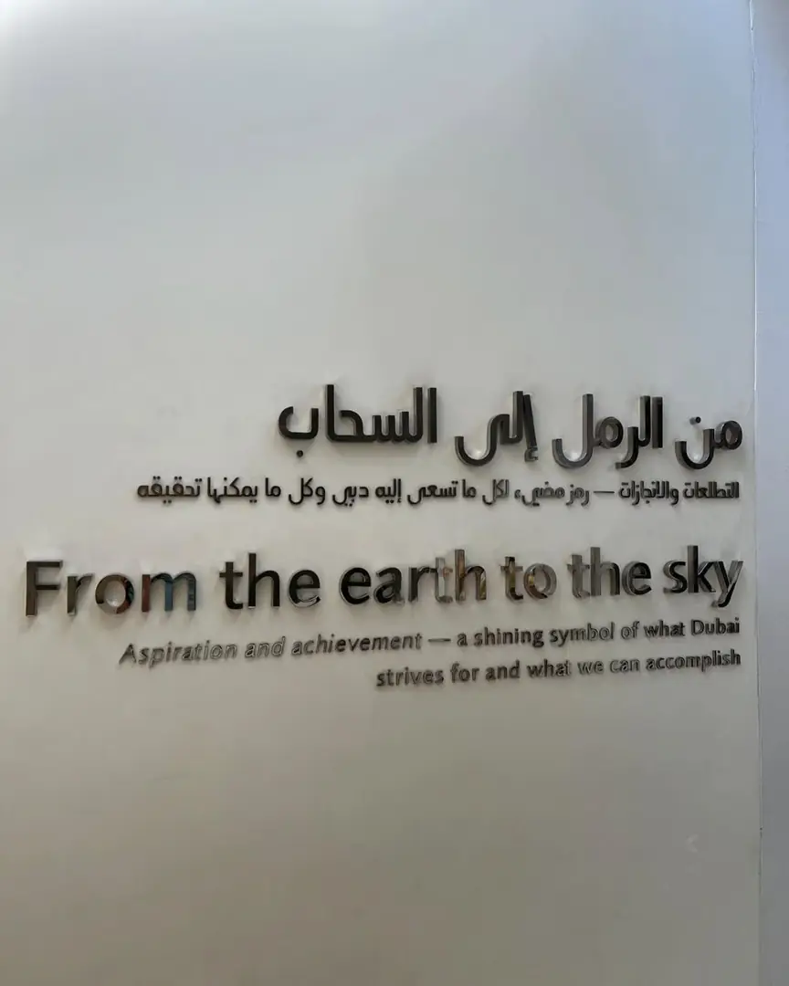 Wall text in Arabic and English reading From the earth to the sky, Dubai. Photograph by Arav Jain.